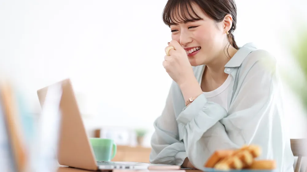 ノートパソコンでオンラインコンテンツを利用している女性の画像