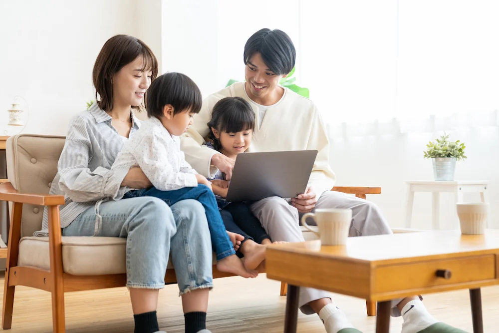 家族4人がリビングでノートパソコンを見ている画像