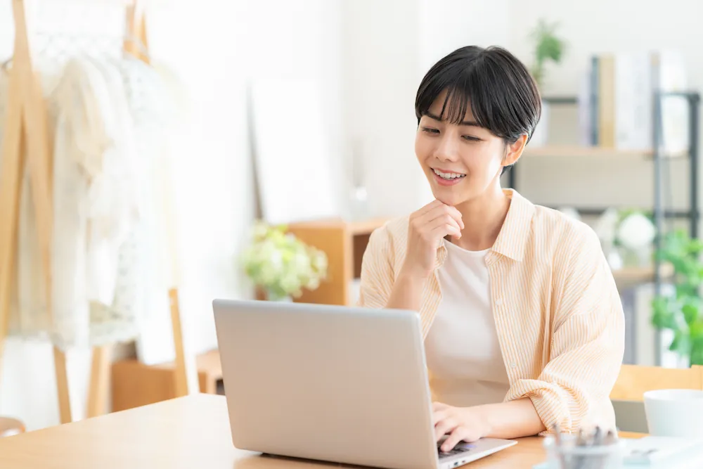 自宅でパソコンを使ってインターネットを利用する女性のイメージ画像